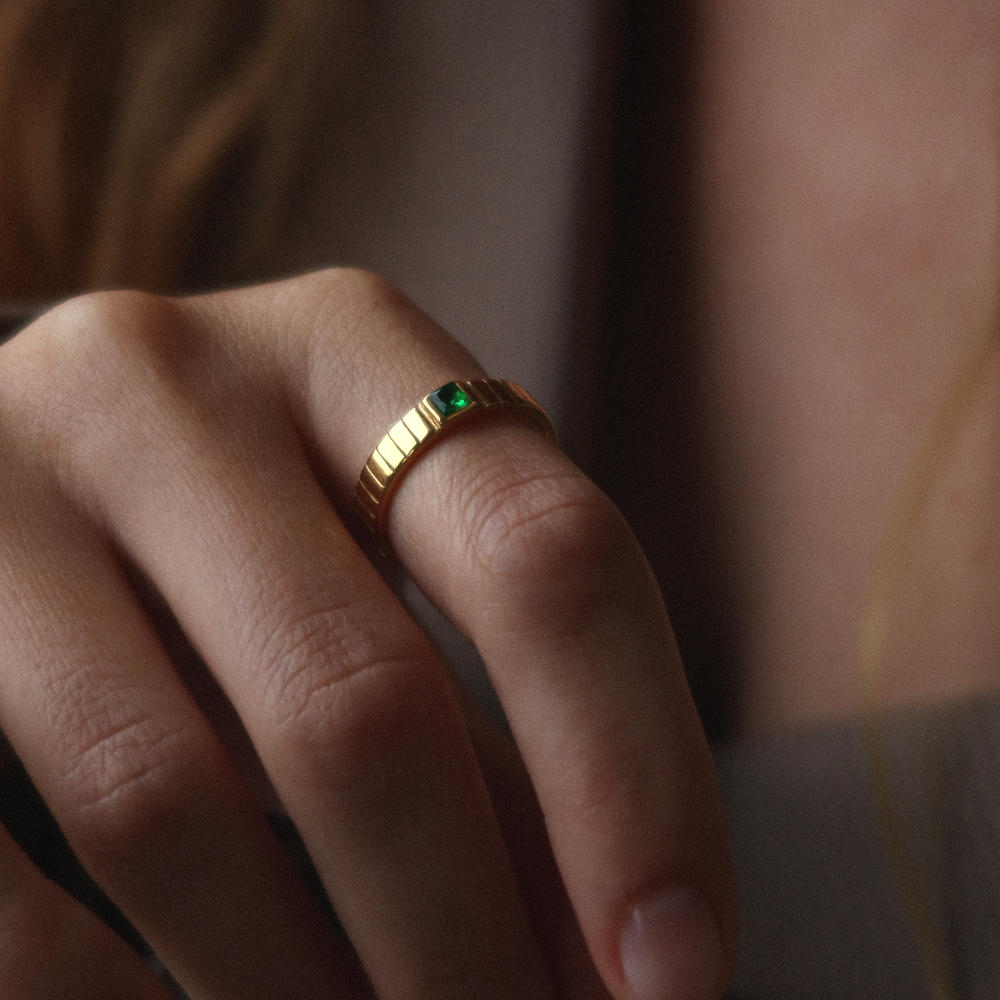 Unisex gold band ring from Rush featuring a ribbed design and green square-cut stone, blending minimalist elegance with a bold accent detail. rush gold ring with green emerald gemstone men women trendy popular chic ring 