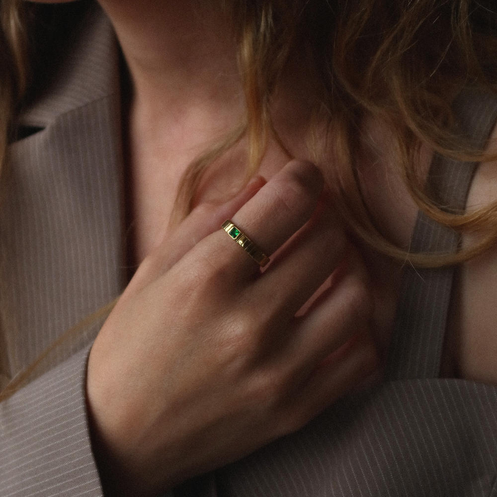 Unisex gold band ring from Rush featuring a ribbed design and green square-cut stone, blending minimalist elegance with a bold accent detail. rush gold ring with green emerald gemstone men women trendy popular chic ring 