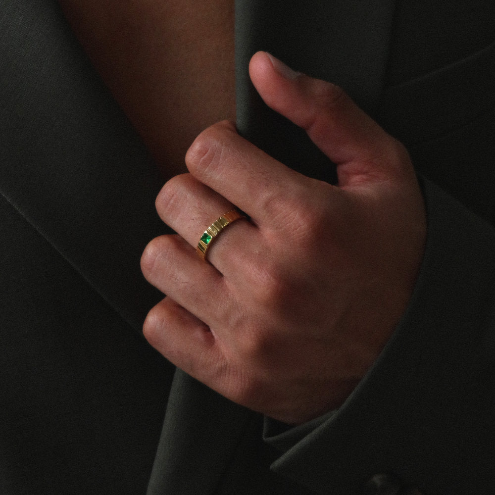 Unisex gold band ring from Rush featuring a ribbed design and green square-cut stone, blending minimalist elegance with a bold accent detail. rush gold ring with green emerald gemstone men women trendy popular chic ring 