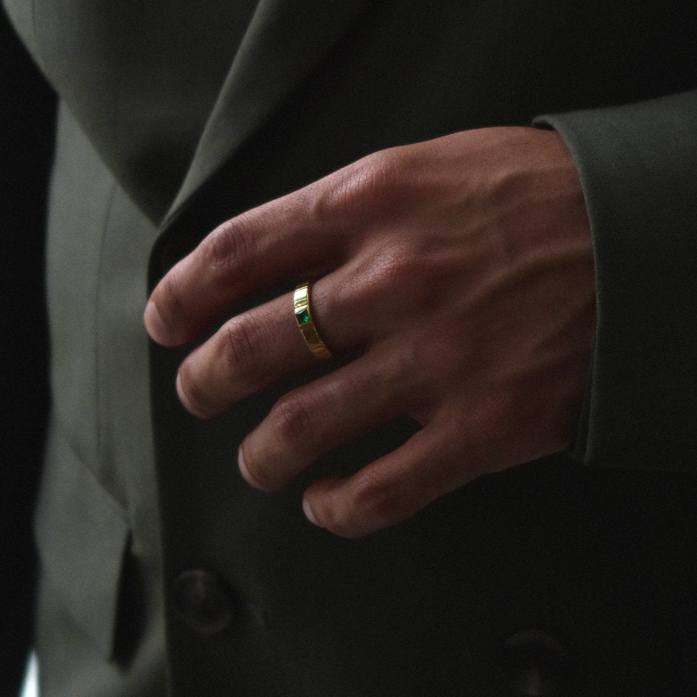 Unisex gold band ring from Rush featuring a ribbed design and green square-cut stone, blending minimalist elegance with a bold accent detail. rush gold ring with green emerald gemstone men women trendy popular chic ring 